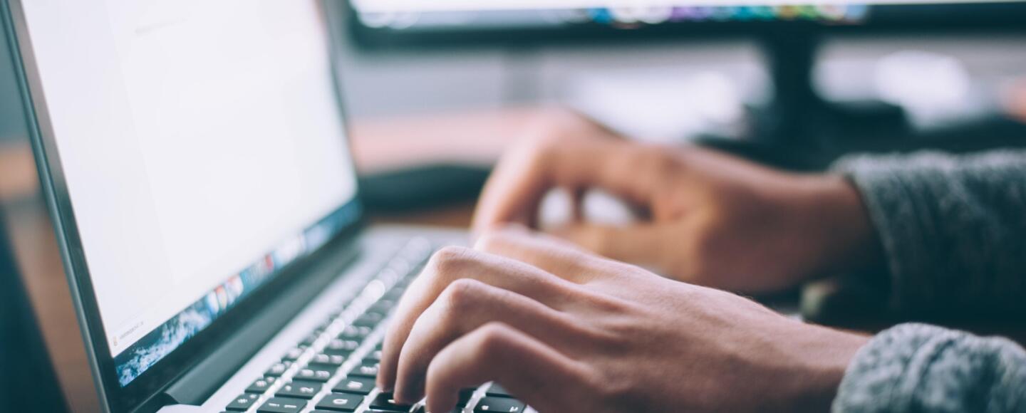 Someone typing on an apple laptop