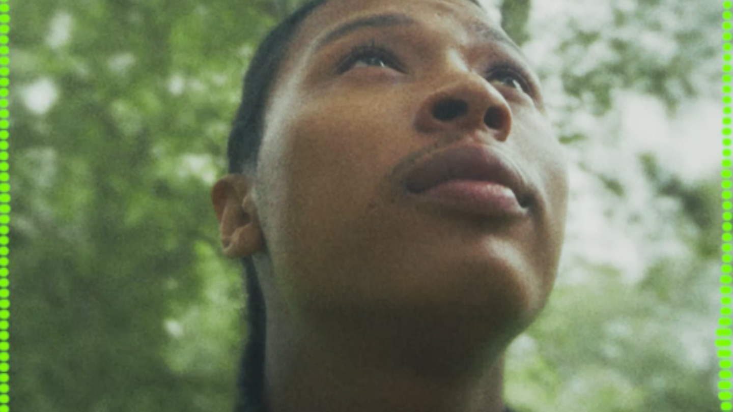 Musician outdoors looking upwards wearing headphones around his neck