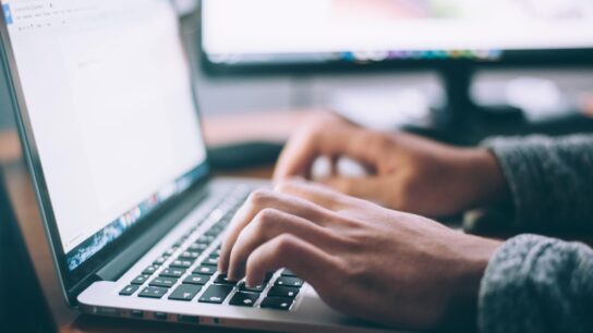 Someone typing on an apple laptop